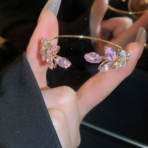 Close-up of sparkling leaf-shaped crystals on a refined gold bangle for women