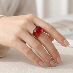Detailed view of a silver ring with large faceted deep red gemstone on white linen fabric