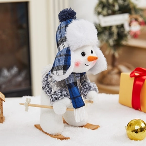 Skiing snowman plush figure with blue plaid hat and wooden skis on a snowy surface
