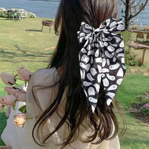 Detail view of a large black Halloween bow clip with white ghost patterns on a model's hair