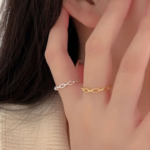 Close-up of stacked gold and silver chain rings on finger showing metal texture