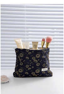 Detail of dark blue floral makeup bag with gold daisy embroidery and zipper closure