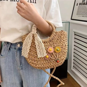 Detail der Strohhandtasche mit floralen Akzenten und einer weißen Spitzenschleife