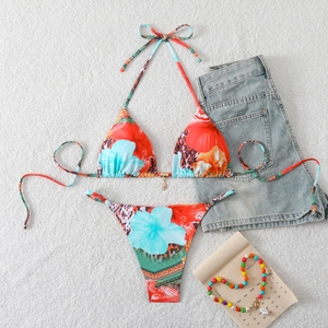 Flat lay of a bikini set with tropical floral print and a starfish metal pendant detail