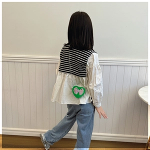 Rear view of a girl wearing a white sailor top with a green heart butterfly crossbody bag