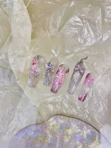 Detail of pink gradient long coffin press-on nails with 3D bows and Christmas charms