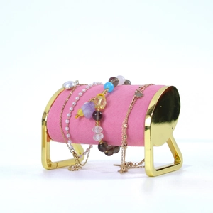 Detail of pink velvet jewelry display stand with golden metal supports for bracelets