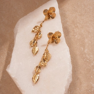 Golden flower and leaf drop earrings with hammered texture on a white stone base