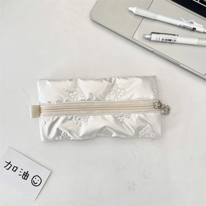 Detail of white quilted bubble pencil case with bow embroidery and flower zipper pull