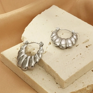 Gros plan de boucles d'oreilles en U argentées texturées sur pierre avec surface ondulée