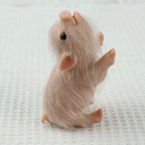 Realistic silicone pig stress relief toy with white fur standing on a white waffle fabric