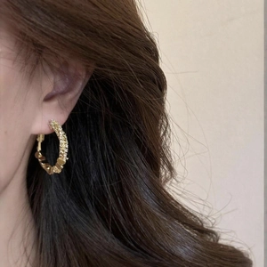 Macro shot of gold hoop earrings with pavé crystals for women's jewelry collection