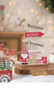 Close-up of wooden Christmas welcome sign with Santa and gift motifs in cozy lighting