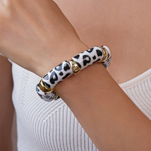 Close-up of black and white leopard print acrylic beads with polished gold metal spacers