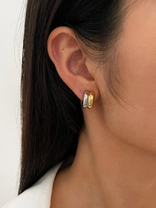 Close-up detail of mixed-metal drop C-shaped earrings on model for a modern look