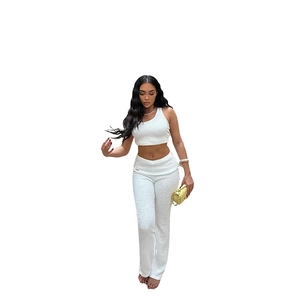Detail of white two-piece set featuring textured halter crop top and slim high-waist trousers