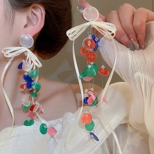Detail of ribbon bow earrings with colorful sequins and long tassels on ear hooks