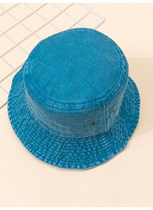 Vue de dessus d'un bob en jean bleu délavé montrant sa texture vintage sur fond beige