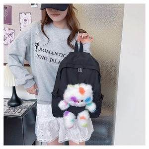 Dettaglio dello zaino in nylon nero con un gatto di peluche colorato e spalline regolabili