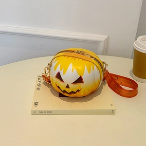 Detail view of yellow pumpkin smile shoulder bag on a magazine with orange strap