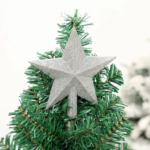 Sparkling silver glitter five-pointed star topper on green Christmas tree branch