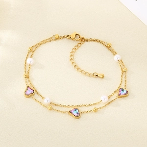 Detail of 18K gold anklet with heart pendants, pearls and iridescent stones on fabric