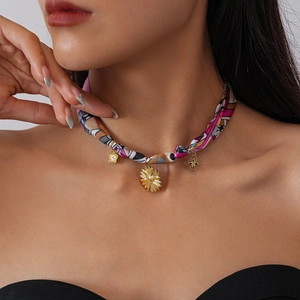 Detailed close-up of a floral printed fabric choker with golden sunflower and clover pendants