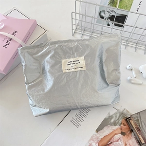 Detail of silver metallic makeup bag with crinkled foil texture on a white desk