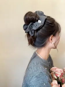 Detail of dark grey polka dot fabric scrunchie worn on a bun with French style