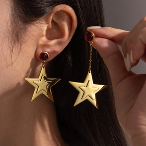 Double-layered gold star earrings with ruby stud shown on model for women