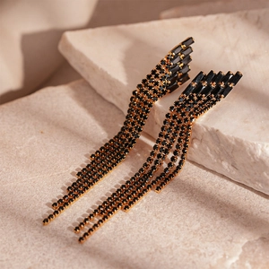 Détail de boucles d'oreilles de luxe à pampilles dorées avec design géométrique et zircons