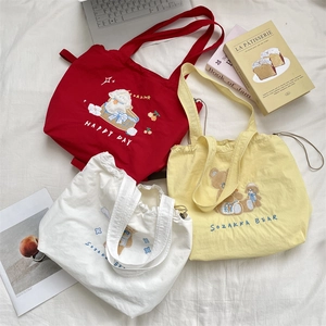Detailed embroidery on canvas tote bags in red, cream and yellow with drawstring closure