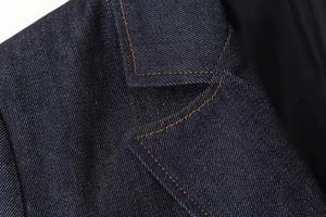 Detalle de las costuras y el cuello de mezclilla azul oscuro en esta chaqueta de moda