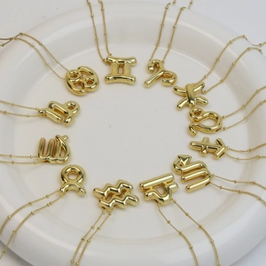 Polished gold bubble 12 zodiac constellation pendant necklaces arranged on a tray