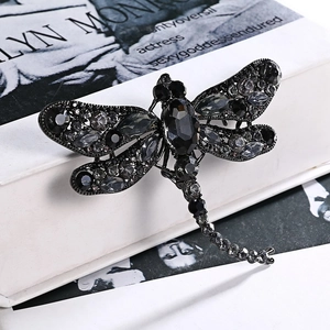 Macro shot of detailed dragonfly brooch featuring dark crystals and a vintage grey finish