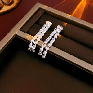 Close-up of sparkling silver double-row zircon earrings on a luxury velvet display