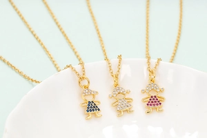 Macro shot of colorful zircon-studded boy and girl charms on golden chain necklaces