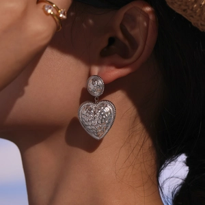 Boucles d'oreilles cœur en argent texturé avec plaquage or 18K portées par un mannequin