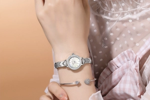 Silver quartz watch with rhinestone bezel and matching heart arrow bracelet on a wrist