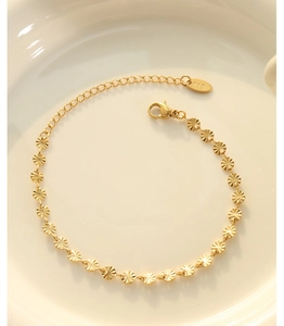 Detailed macro view of gold circular radiating embossed link chain bracelet in ceramic tray