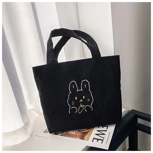 Detail of black corduroy tote bag featuring a cute white rabbit embroidery and soft texture