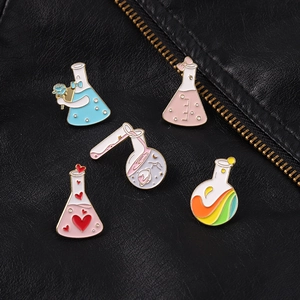 Dettaglio di spillette creative in smalto a forma di provette con motivi a cuore e arcobaleno