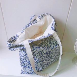 Detailed view of blue floral canvas tote bag featuring interior pocket and woven handles