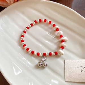 Detail of beaded bracelet featuring ceramic crystals and a polished silver cherry charm