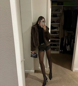 Mirror selfie showing a brown faux fur jacket paired with black leather shorts and heels