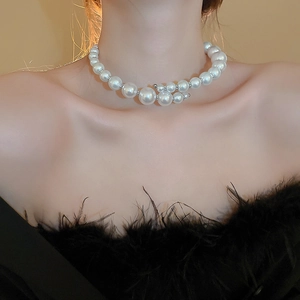 Detailed view of elegant faux pearl necklace with silver beads on model neck