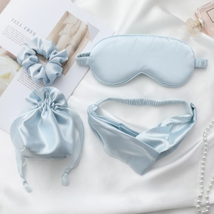 Light blue silk sleep set including eye mask, scrunchies, and headband in a drawstring bag