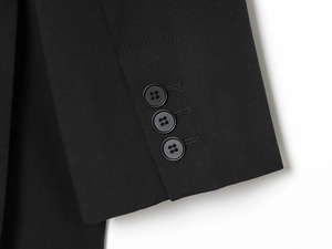 Détail du poignet d'un blazer noir avec trois boutons sur un tissu sergé fin