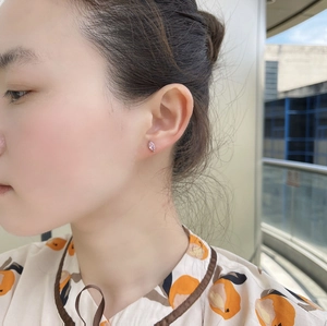 Close-up of a pink marquise zircon stud earring worn by a model in outdoor setting