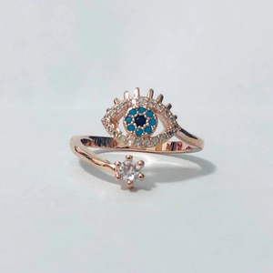 Detalle de anillo en oro rosa con ojo turco azul y un pequeño acento floral boho